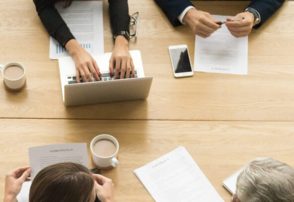 Diverse business colleagues working together at meeting, vertica Diverse business colleagues working together talking planning at meeting table, multiracial young and senior people preparing for contract negotiations talking during teamwork, vertical top view