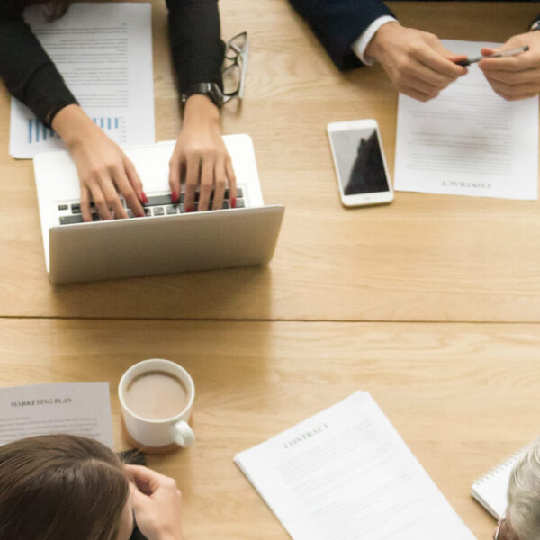 Diverse business colleagues working together talking planning at meeting table, multiracial young and senior people preparing for contract negotiations talking during teamwork, vertical top view
